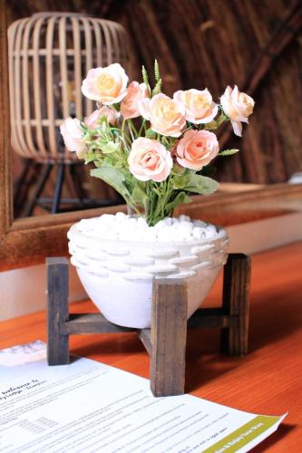 a white vase filled with pink roses on a table at Olive Country Lodge - Eswatini in Ngwempisi