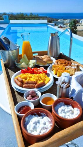 a tray of breakfast food on a table next to a pool at Acrothea Suites and Villas - Akrotiri Caldera - Santorini in Akrotiri
