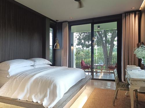 a bedroom with a large bed and a table and chairs at Chombua MaeWang ชมบัว in Chiang Mai