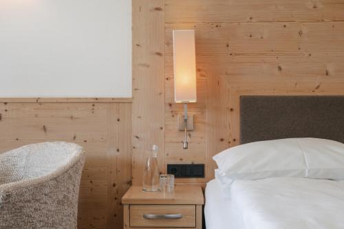 a bedroom with a white bed and a wooden wall at Brunelle Seiser Alm Lodge in Alpe di Siusi