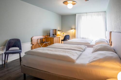 a hotel room with two beds and a window at Mercure Hotel Pforzheim in Pforzheim