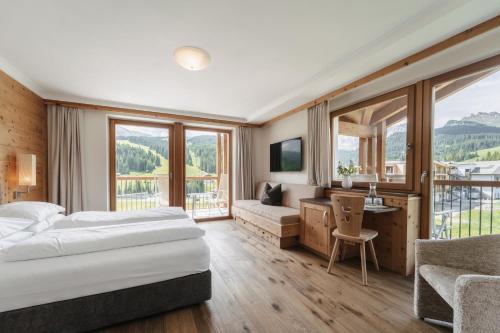a hotel room with two beds and a desk at Brunelle Seiser Alm Lodge in Alpe di Siusi