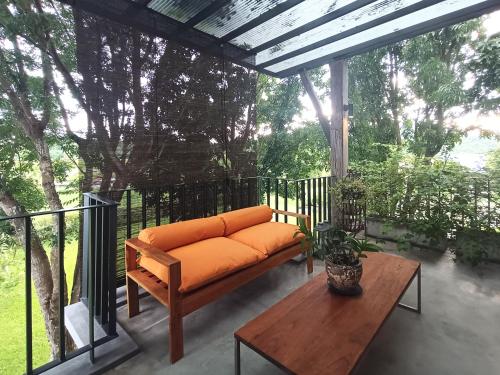 an orange couch on a porch with a table at Chombua MaeWang ชมบัว in Chiang Mai