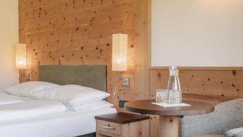 a bedroom with a bed and a table with a lamp at Brunelle Seiser Alm Lodge in Alpe di Siusi