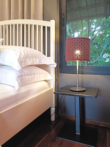 a lamp on a table next to a bed at Chombua MaeWang ชมบัว in Chiang Mai