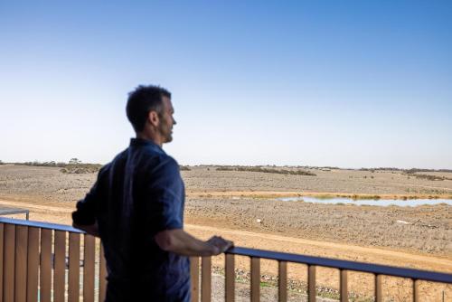 a man standing on a fence looking out at the desert at Monarto Safari Resort in Monarto