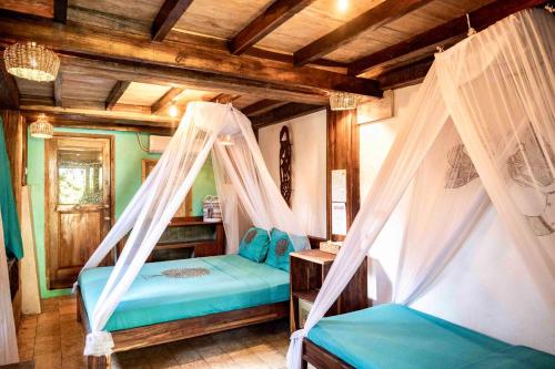 a bedroom with two beds in a room with wooden ceilings at Villa Monyet Java in Batukaras