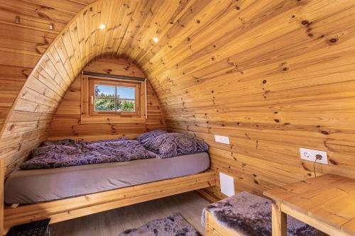 a bed in a log cabin with a window at Campingpod Auf Der Alpakawiese in Arnsberg