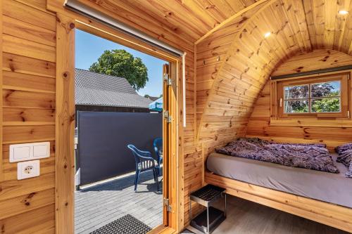 a bedroom in a wooden cabin with a large window at Campingpod Auf Der Alpakawiese in Arnsberg