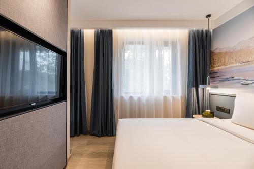 a bedroom with a large white bed and a television at Atour Light Hotel Temple of Heaven in Beijing