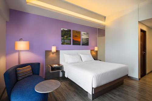 a bedroom with a white bed and a chair at Mercure Padang in Padang