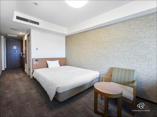 a hotel room with a bed and a chair at Daiwa Roynet Hotel Naha Omoromachi in Naha