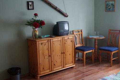 a tv on a cabinet with two chairs and a table at Penzion Olga in Mariánské Lázně