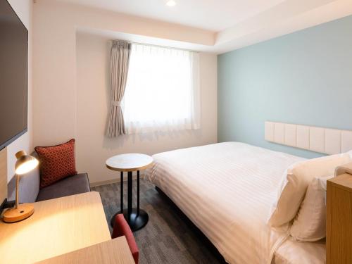 a bedroom with a bed and a table and a window at Comfort Hotel Kii Tanabe in Tanabe