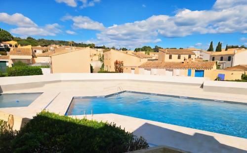 - une piscine dans une villa avec des bâtiments en arrière-plan dans l'établissement Studio Cabine avec Piscine et Place de parking privée CAP D'AGDE, au Cap d'Agde