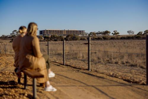 two people sitting on a bench in front of a fence at Monarto Safari Resort in Monarto