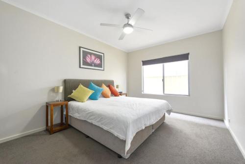 ein weißes Schlafzimmer mit einem Bett mit bunten Kissen in der Unterkunft The Cove in Port Hughes