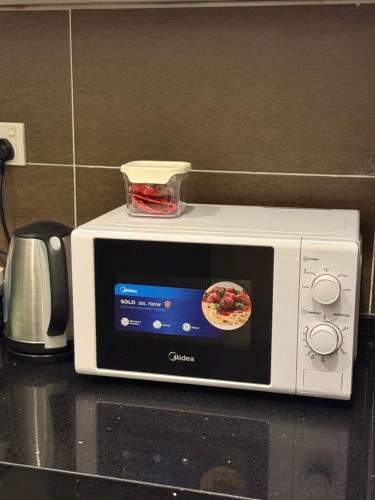 a white microwave on a counter with a pizza on it at Cozy 2 BR Apartment w/ Pool Gym Wi-Fi & Work Space in Klang
