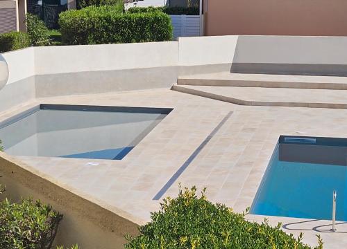 une piscine sur un patio avec deux escaliers et une piscine dans l'établissement Studio Cabine avec Piscine et Place de parking privée CAP D'AGDE, au Cap d'Agde