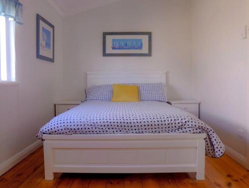 a white bed with a yellow pillow in a bedroom at The Little White House in Port Vincent