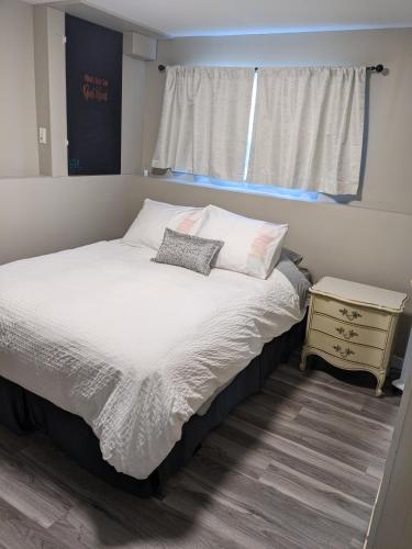 a bedroom with a bed and a window and a nightstand at Private SweetSuite 1 Bdrm Bathroom mini-kitchen in Kamloops
