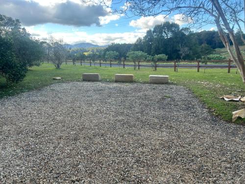 three stone benches sitting on a gravel field at Bello BigRig Luxury Riverfront Escape Close to Town in Bellingen