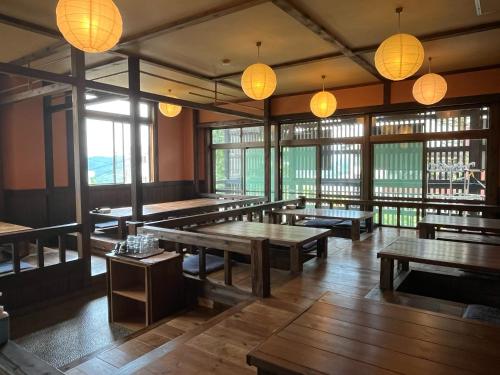 a restaurant with wooden tables and lights and windows at Matsunoki-tei in Otari
