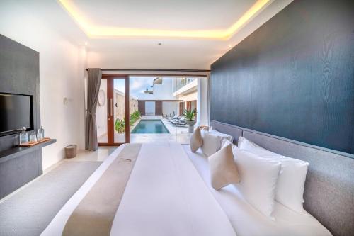 a bedroom with a large white bed and a tv at Cosy and Luxurious Villa Sentosa Seminyak in Seminyak