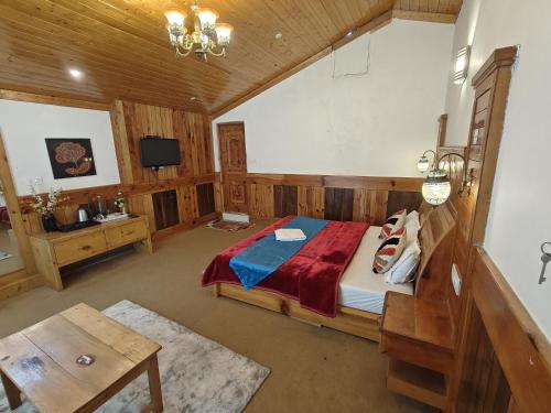 a bedroom with a bed and a table and a tv at Apple Garden Cottage in Manāli
