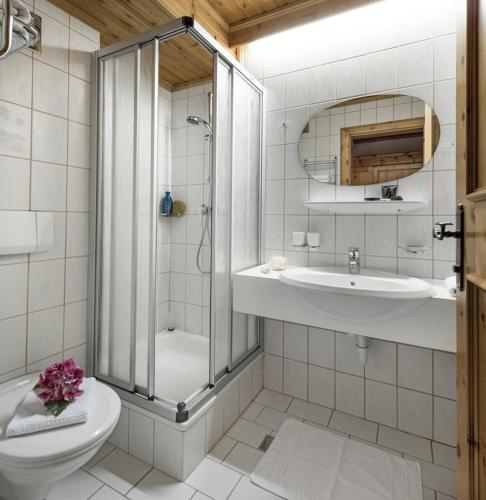 a bathroom with a shower and a toilet and a sink at Hotel Hubertushof in Grossarl