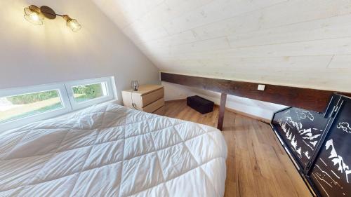 a bedroom with a large bed and two windows at Pagotin de charme à Métabief in Métabief