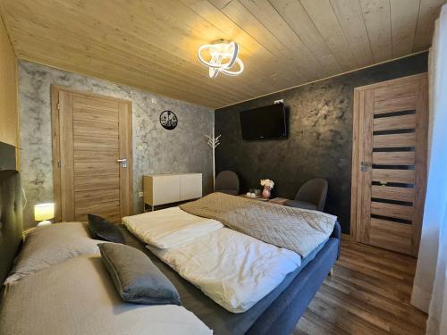 a bedroom with two beds and a tv on the wall at Wellness Toliar Tatry in Stará Lesná
