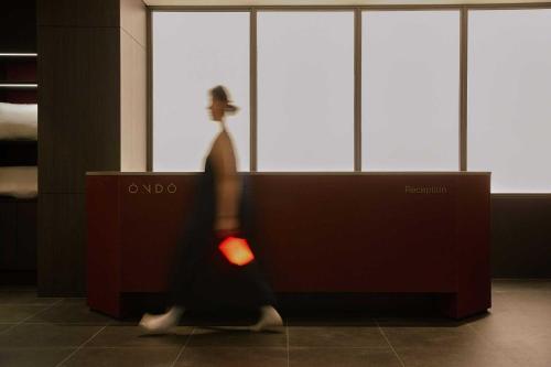 a woman walking past a wall in a building at Ondo Hotel and Spa Jongno by Aank in Seoul
