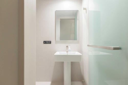a white bathroom with a sink and a mirror at Ondo Hotel and Spa Jongno by Aank in Seoul