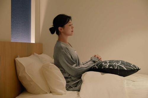 a woman sitting on top of a bed at Ondo Hotel and Spa Jongno by Aank in Seoul