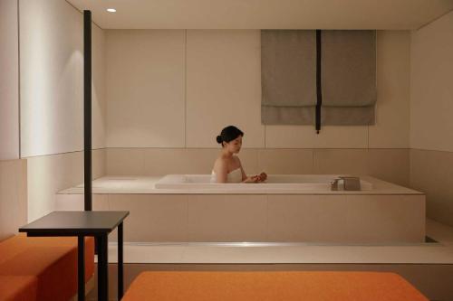 a woman is sitting in a bath tub at Ondo Hotel and Spa Jongno by Aank in Seoul