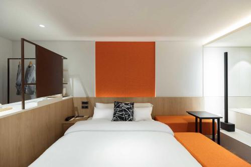 a bedroom with a large white bed with an orange headboard at Ondo Hotel and Spa Jongno by Aank in Seoul