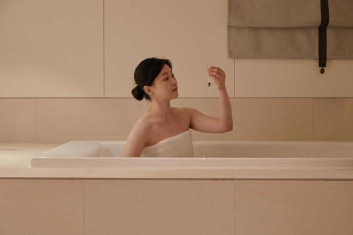 a woman standing in a bath tub with afinger at Ondo Hotel and Spa Jongno by Aank in Seoul