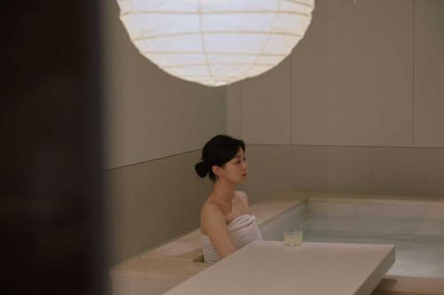 a woman is sitting in a bath tub at Ondo Hotel and Spa Jongno by Aank in Seoul