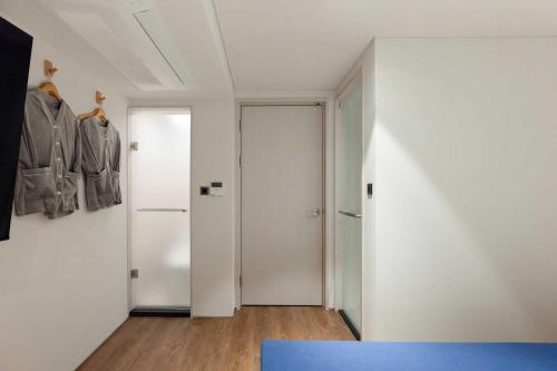 a room with white walls and a hallway with two closets at Ondo Hotel and Spa Jongno by Aank in Seoul