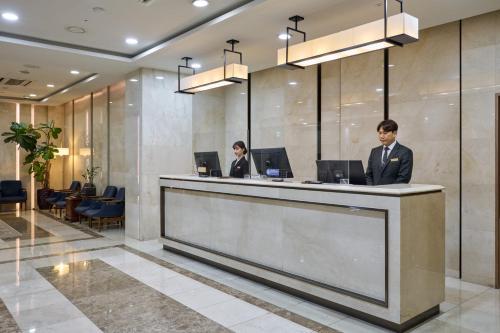 two people standing at a reception counter in a lobby at Summit Hotel Seoul Dongdaemun in Seoul