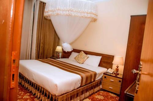 a hotel room with a bed with a curtain and a window at Ineza Hotel Musanze - Snow Hotel in Ruhengeri