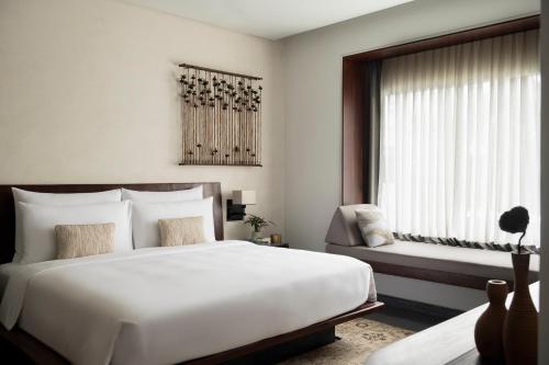 a bedroom with a large white bed and a window at Treeline Urban Resort in Siem Reap