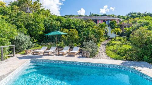 a swimming pool with lounge chairs and an umbrella at Charming villa with fantastic views of the ocean in Pointe Milou