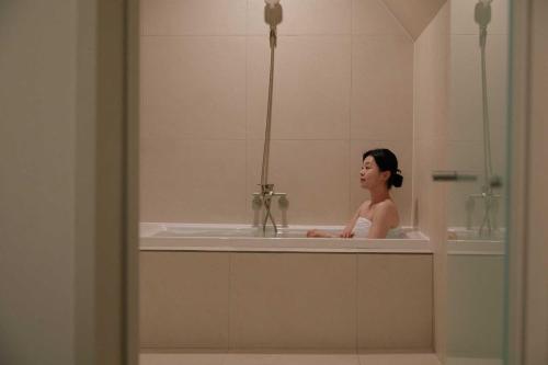 a woman sitting in a bath tub in a bathroom at Ondo Hotel and Spa Jongno by Aank in Seoul