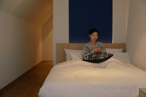 a woman sitting on top of a bed at Ondo Hotel and Spa Jongno by Aank in Seoul