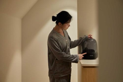 a woman is standing next to a black appliance at Ondo Hotel and Spa Jongno by Aank in Seoul
