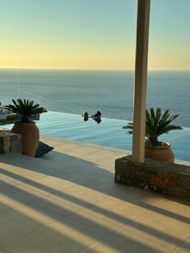 a person swimming in a swimming pool next to the ocean at Maison Meltem in Agia Pelagia