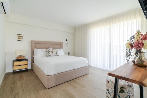a white bedroom with a bed and a vase of flowers at Quinta do Outeirinho - Villa Deluxe in Celorico de Basto