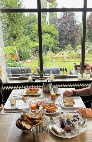 een tafel met borden eten naast een raam bij De Post B&B Restaurant in Klimmen